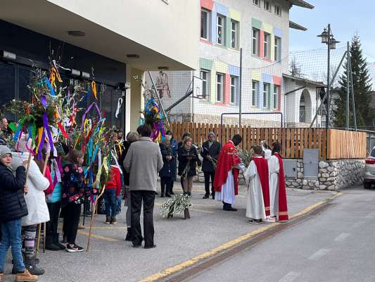 Siur Andrea benedësc l'orí denanco jí adöm cun la comunité en prozesciun te dlijia a zelebré la santa mëssa. 
