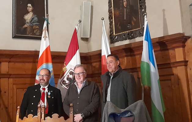 I raprejentanc de la trei comunitèdes Detomas, Gilmozzi e Zelger dedant a la bandieres.
